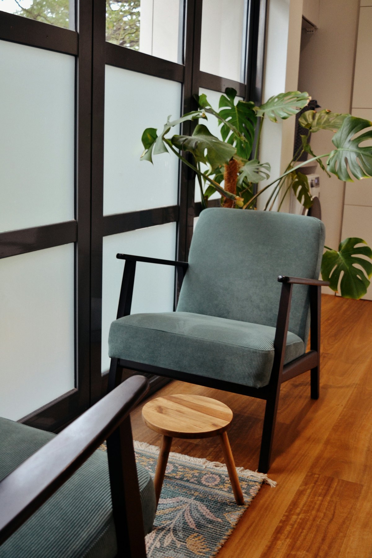 A calm sitting area with a sage armchair and a leafy plant